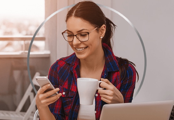 Femme au travail devant son ordinateur son café et téléphone entre ses mains