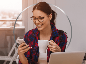 Femme au travail devant son ordinateur son café et téléphone entre ses mains